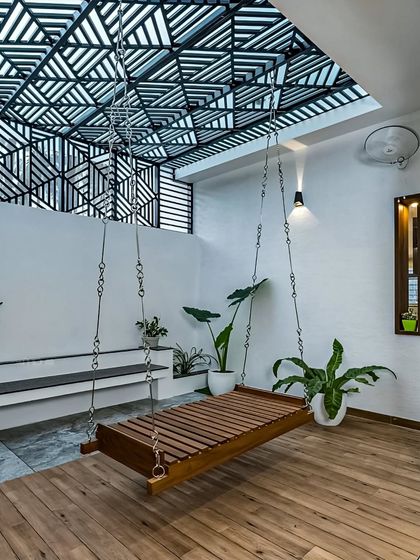This spacious patio area features a modern wooden swing bed suspended from a geometric patterned ceiling. It's the ultimate spot for lounging and enjoying a lazy afternoon.