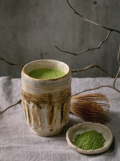 A beautifully rustic, hand-carved matcha bowl, complete with a whisk and matcha powder.