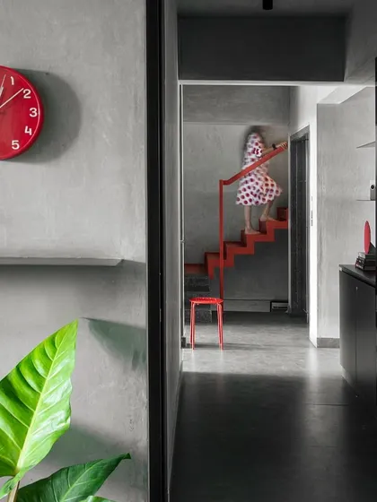 A bright red clock and a matching red staircase create deliberate "streaks of color" in our otherwise neutral office. These elements act as visual anchors and distractions, drawing attention to circulation paths and adding a playful touch to the industrial aesthetic.