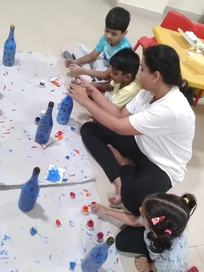 Children engrossed in a bottle painting session, guided by an instructor. This activity is a fun way to learn about color mixing and design.