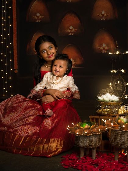 A heartwarming photo of an older sister holding her smiling baby brother during their Diwali photoshoot. The love between them is so clear to see.