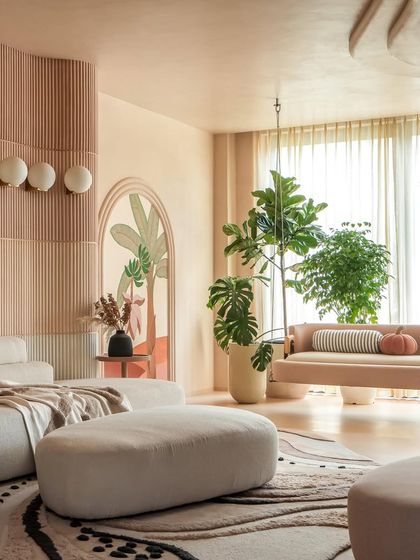 This living room from our award-winning "Marshmallow" project features soft, organic furniture and a palette of warm, neutral tones. The fluted wall panels and arched mural add texture and artistry to the calm space.