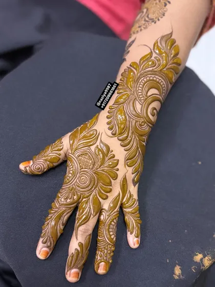 This design features bold, flowing leaves and spirals that cover the entire back of the hand. It's a classic Arabic henna style that is always in demand.