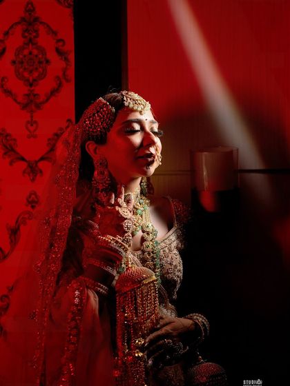The beauty of a bride under the veil. This photo captures a classic moment, with the sheer dupatta softening the look while the makeup still shines through, especially the bold eyes and defined features.