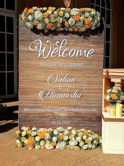 A close-up of the rustic yet elegant wooden welcome sign, adorned with fresh white and peach roses. It's these details that make a wedding feel personal and unique.
