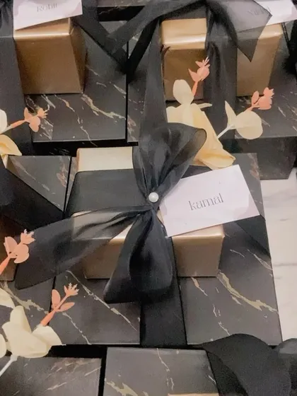 A close up of our black marble groomsmen gift box. The combination of the gold inner box, black ribbon, and delicate floral accent creates a look of pure luxury.