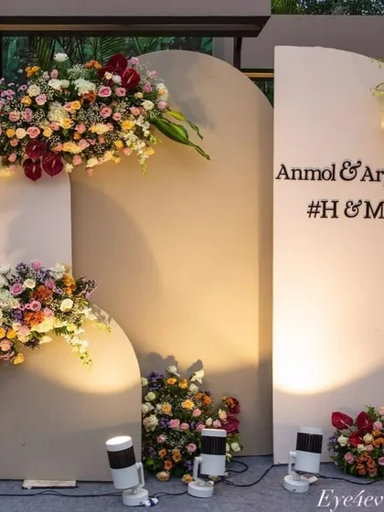 A chic and modern engagement photo backdrop. We used minimalist arched panels, personalized with the couple's names, and accented them with beautiful, multi-colored floral arrangements and spotlights.