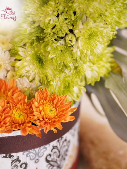 A detailed close-up of the heart-shaped arrangement, focusing on the texture of the green chrysanthemums and the vibrant orange daisies below. This shows the precision required for such a creative floral design.