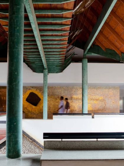 A walkway overlooks one of the main courtyards at the LMW Headquarters. The design uses changes in level and material, such as the green-painted steel and red wood, to articulate the circulation paths and frame views.