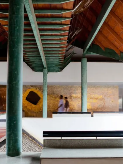 A walkway overlooks one of the main courtyards at the LMW Headquarters. The design uses changes in level and material, such as the green-painted steel and red wood, to articulate the circulation paths and frame views.