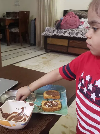 A student carefully adds sprinkles to her chocolate rusk creation. Activities like this are a great sensory experience and help develop coordination and focus.