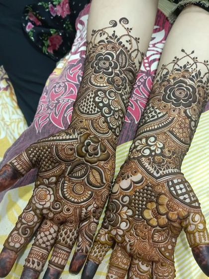 A lovely bridal design with a mix of bold floral work and delicate, intricate patterns covering the hands and arms.
