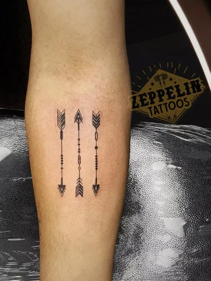A set of three minimalist arrow tattoos. This style requires a steady hand and an understanding of symmetry, which are fundamental skills we practice from day one.