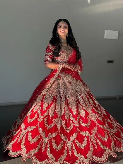 For a reception or sangeet, I love creating glamorous looks like this. This bride is wearing a stunning red and gold lehenga, and I've designed a bold makeup look with soft waves to match the celebratory feel of the event.