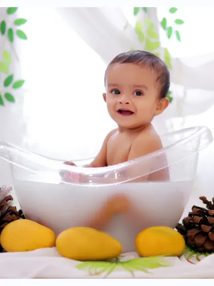 A happy baby boy enjoying a milk bath session, surrounded by mangoes for a unique and colorful twist.
