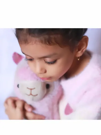 A tender moment between a girl and her favorite stuffed llama. Incorporating a child's favorite toy into a photoshoot makes them feel comfortable and helps capture their loving, gentle nature.