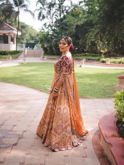 A back view of the bride, showing off her beautiful lehenga and the elegant hairstyle. This look is all about grace from every angle.