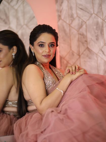 Posing by the mirror, she looks effortlessly chic. The makeup is soft and pretty, perfect for any special occasion.