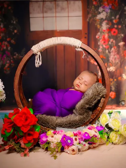 A peaceful newborn photo in a circular wooden swing prop, surrounded by a garden of flowers. My studio sets are designed to create beautiful, imaginative scenes.