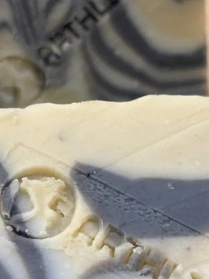 A close-up of the intricate swirl design and our brand stamp on the Charcoal & Dead Sea Mud Soap. Each bar is a unique piece of art.