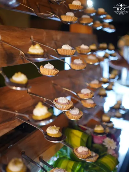 An elegant display of our miniature fruit tarts. Each tartlet is individually placed on a spoon for easy serving, showcasing the delicate pastry work and creamy fillings.