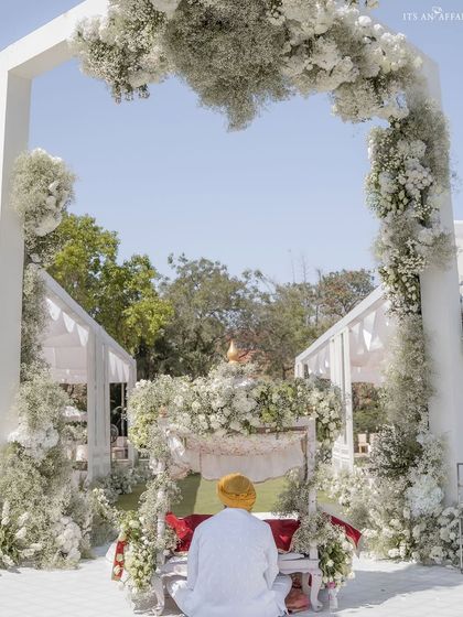 A serene moment at an Anand Karaj ceremony by Lake Pichola. The setup is a vision in white, with a modern floral arch framing the sacred space, creating a peaceful and spiritual atmosphere.