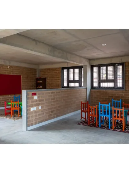 A classroom space at the Mathru Centre. We used low, exposed brick walls to partition the space, creating distinct activity zones without closing off the room entirely. The colorful furniture adds a playful touch.