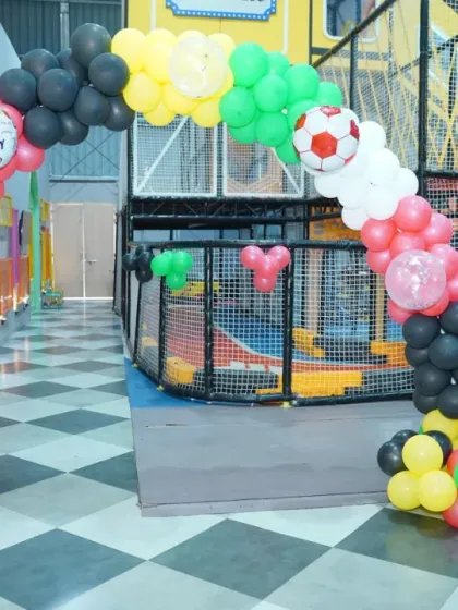 A balloon arch decorated with soccer and basketball balloons leads into a sports-themed party area, complete with cutouts of famous football players.