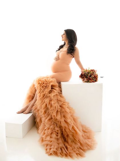 A modern and artistic pose on white blocks. The contrast between the minimalist props and the textured boho gown is so cool.