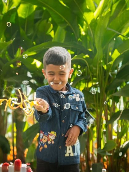 A candid shot of a young guest enjoying the party activities. The bubbles and his happy expression create a magical and joyful atmosphere.