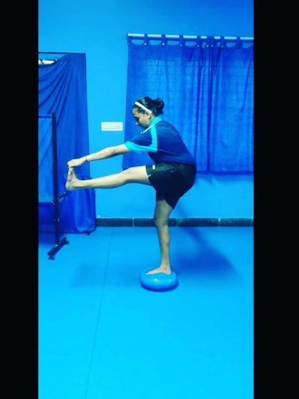 A player works on her hamstring flexibility and balance. This type of targeted stretching is essential for powerful leg movements and preventing muscle strains during intense matches.