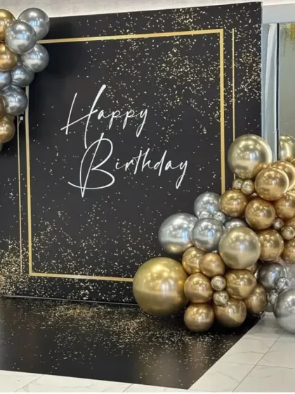 A glamorous black, gold, and silver birthday backdrop. The sparkling black panel is framed by a metallic balloon arrangement, creating a luxurious and high-end look.