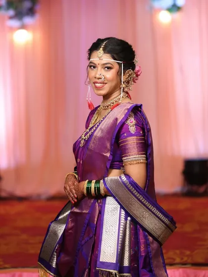 A smiling portrait of the bride, showcasing her traditional mundavalya (forehead ornament) and radiant makeup.