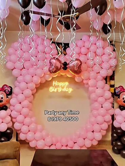 A full view of the large Minnie Mouse balloon sculpture at a home party. This setup includes helium balloons on the ceiling to complete the festive look.