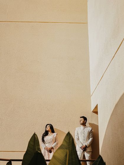 A minimalist composition with the couple positioned against a large, sunlit wall. The use of negative space and clean lines gives this portrait a modern, artistic feel.
