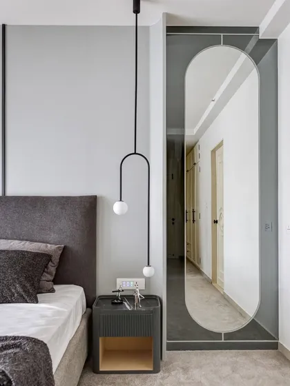We love playing with reflections. A full-length mirror, tinted in grey, creates an illusion of depth and reflects the clean lines of the bedroom. The muted grey walls and custom bedside table complete this picture of modern sophistication.