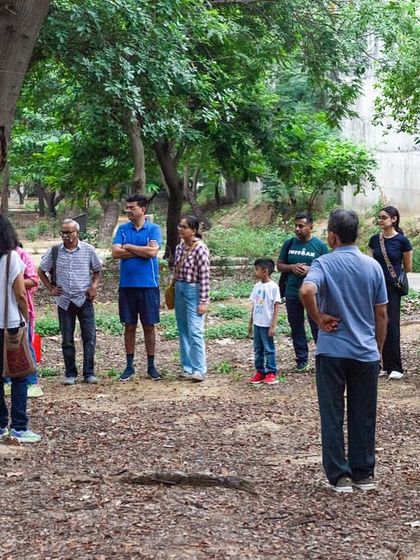 A group of citizens gathers in a clearing at Aravali Creek, listening to stories about the area's restoration and the return of wildlife.