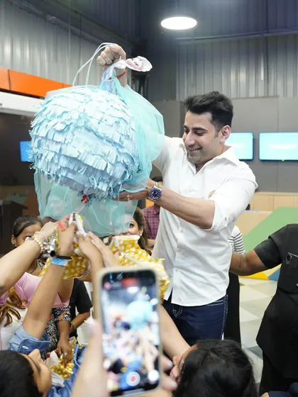 A piñata moment! A father helps the kids break open the piñata, a classic party activity that brings everyone together for a shower of treats.
