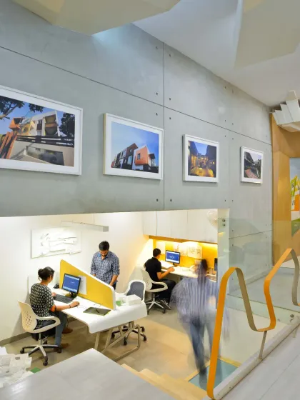 The lower level of my studio houses open workstations, framed by an opening from the floor above. The motion-blurred figures of my team show the dynamic and active nature of our creative workspace.
