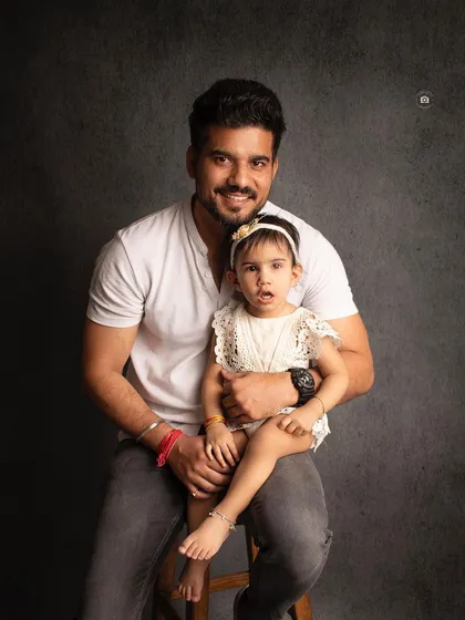 A proud father with his little girl. This classic portrait against a dark backdrop is a simple and beautiful way to capture the father-daughter bond.