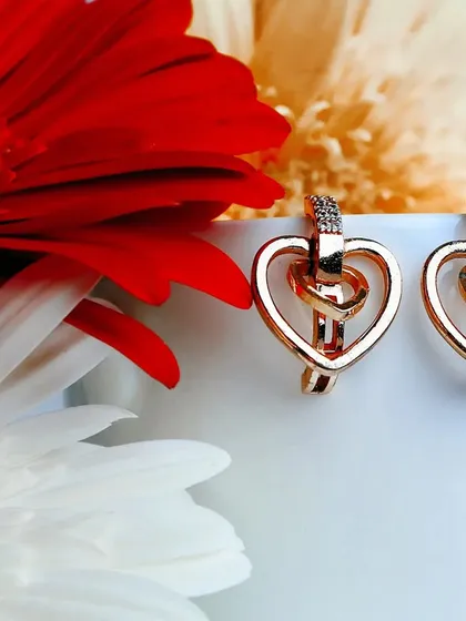 A bright and cheerful product shot of rose gold heart-shaped earrings, styled with vibrant flowers to create a feeling of love and happiness.