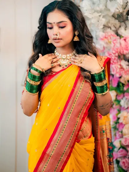 The model looks down, showing off the soft pink and gold eyeshadow that pairs beautifully with the yellow and red saree.