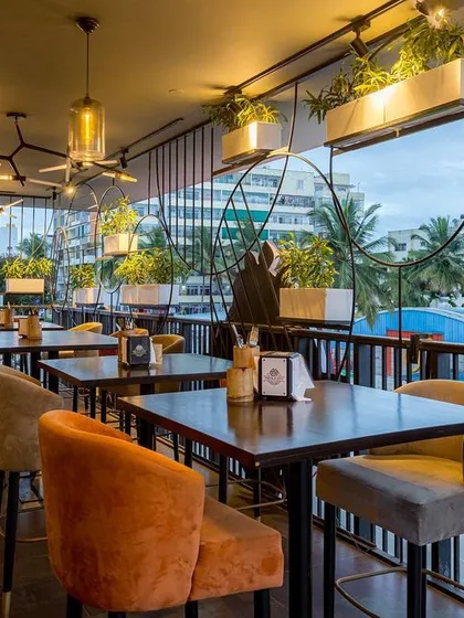 The balcony seating offers guests a prime spot with a view, made safe and stylish by our custom-designed planter grills. The warm tones of the chairs complement the dark metalwork and lush plants.