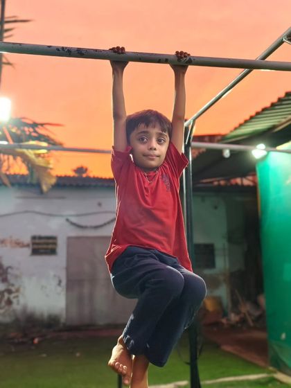 This young athlete enjoys a sunset training session, hanging strong on the bar. The beautiful sky makes the hard work feel a little easier.