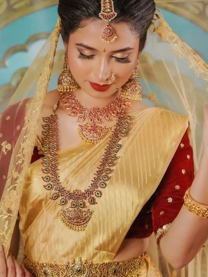 A model looking graceful in our full kemp stone bridal set, paired with a classic gold and red silk saree.