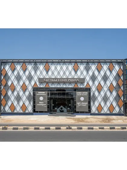 The facade of the Satyam Four Wings retail showroom in Shimoga. We used an industrial approach with a diagrid pattern of metal perforated sheets and ACP cladding to create a modern and visually striking exterior.