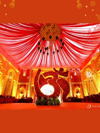 A sacred "Om" symbol, created entirely from red flowers, serves as a powerful and spiritual centerpiece for this traditional Indian wedding.