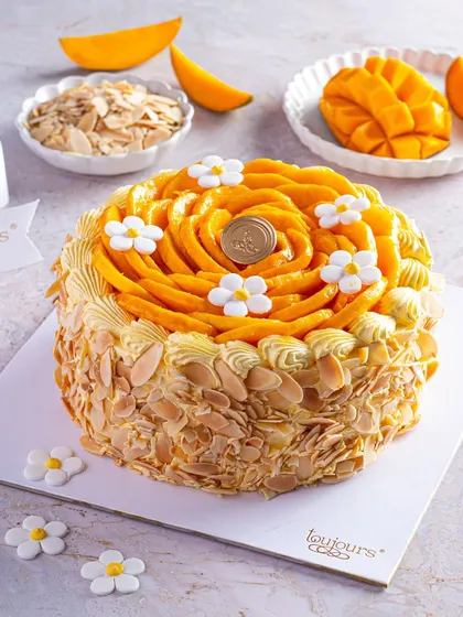 Our signature Fresh Cream Mango Cake, adorned with a beautiful rosette of hand-sliced Alphonso mangoes and delicate sugar flowers. This cake is a celebration of seasonal perfection, with toasted almonds adding a delightful crunch.