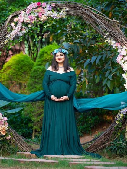 A creative fabric toss in a garden setting. The flowing teal fabric behind the mom-to-be adds a sense of movement and drama to this beautiful outdoor shot.