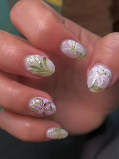 This image shows the full set of lily nails, with each flower painted slightly differently for a natural, artistic feel. This is done on a short, natural nail shape.